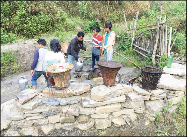 Young people drawing spring water at the brine spring in Kaibi village, Senapati district. A container is meticulously tied to a rope which is then pushed down with the help of a pole for impact, filled and pulled back. (Morung Photo by Pfokrelo Kapesa)