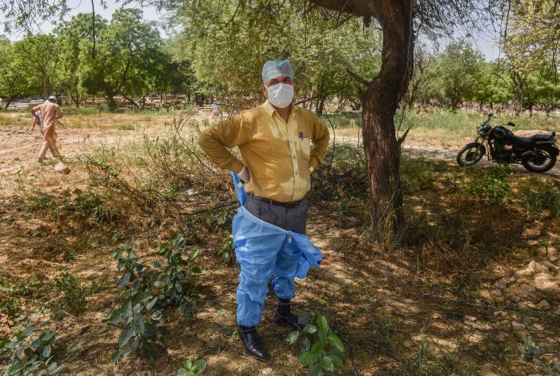 New Delhi: A health worker removes his PPE kit after performing burial of COVID-19 victims at a graveyard, in New Delhi, Thursday, April 8, 2021. (PTI Photo/Manvender Vashist)
