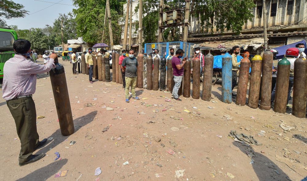 New Delhi: Family members of COVID-19 patients wait outside an oxygen-filling centre to refill their empty cylinders, as demand for the gas rises due to spike in coronavirus cases, at Naraina, in New Delhi, Tuesday, April 27, 2021. (PTI Photo/Manvender Vashist)