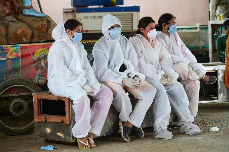 Family members wearing PPE suits, wait for cremation of COVID-19 victims, amid the rise in  cases across the country, in New Delhi on April 29, 2021. (PTI Photo)