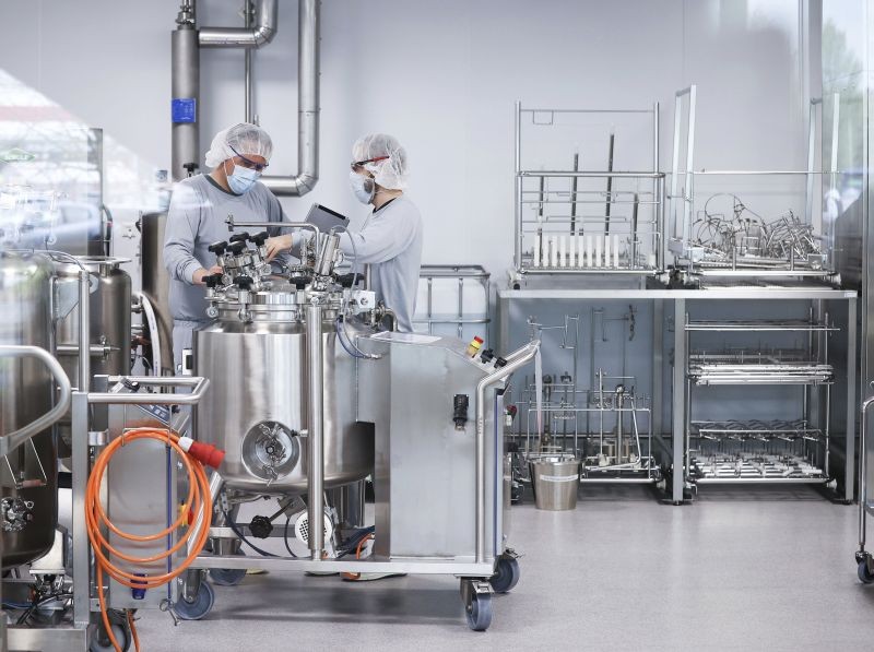 Employees work in the production of Biontech/Pfizer's Comirnaty vaccine at Allergopharma's production facilities in Reinbek, Germany on Friday, April 30, 2021. Around 400 liters of the vaccine are filled in the stainless steel mobile container behind the glass pane in a clean room. Federal Health Minister Spahn visited the plant in Reinbeck near Hamburg on Friday for the symbolic start of production of the vaccine here. (AP/PTI Photo)