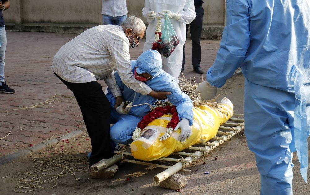 Ahmedabad: Relatives in personal protective equipment crying during last rites of his wife, who died due to the coronavirus disease (COVID-19), before her cremation in Ahmedabad, Saturday, 10 April 2021.(PTI Photo)