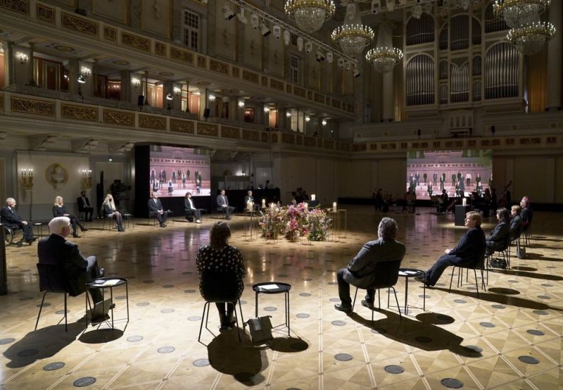 Singer of a choir are seen on video screens as German Chancellor Angela Merkel, fourth right, and German President Frank-Walter Steinmeier, second left, attend a memorial service in Berlin, Germany, Sunday, April 18, 2021 in remembrance of Germany's corona dead. (AP Photo)