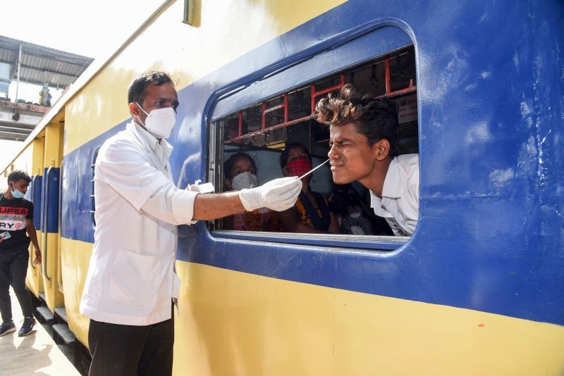 A health worker takes swab sample of a passenger sitting inside a train for COVID-19 test, as coronavirus cases spike across the country, in Patna on April 7. (PTI Photo)