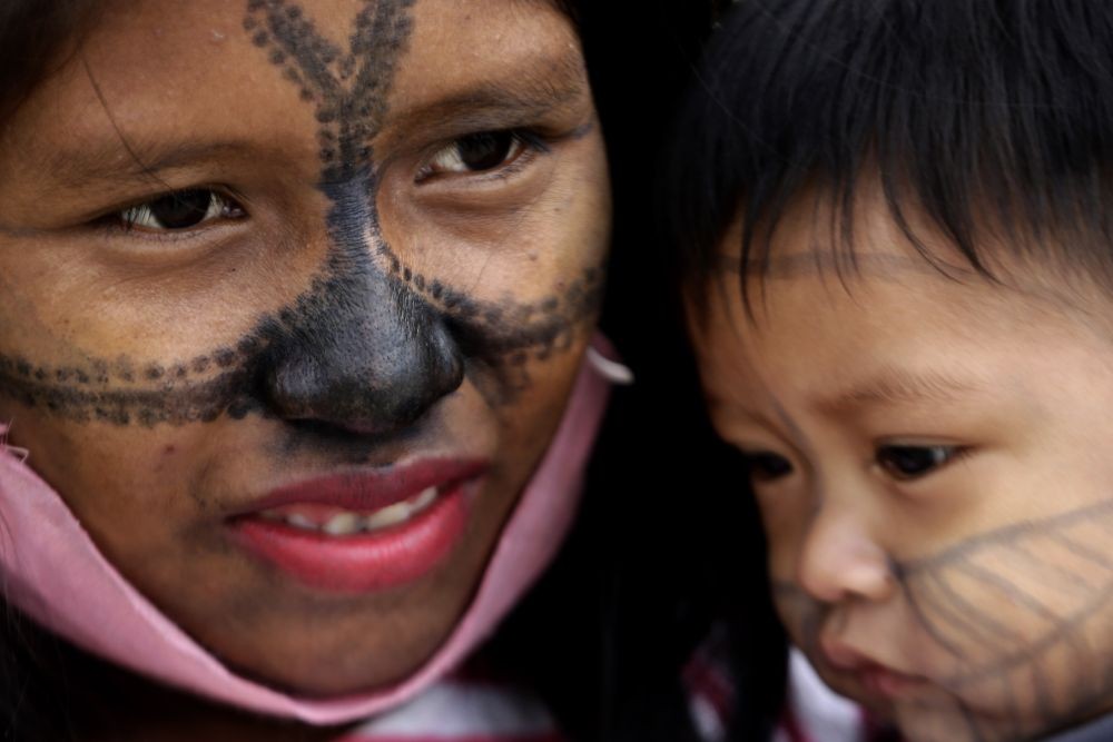 A Munduruku Indigenous woman and child from Alto Tapajos in the Brazilian state of Para attend a show of support for a government decree legalizing mining on Indigenous land outside the Supreme Court in Brasilia, Brazil, Monday, April 19, 2021. (Photo by Eraldo Peres/AP Photo)