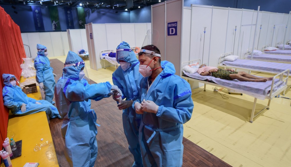 Medics sanitise their hands inside Covid emergency ward at Yamuna Sports complex, as coronavirus cases surge across the country, in New Delhi on April 21. (PTI Photo)