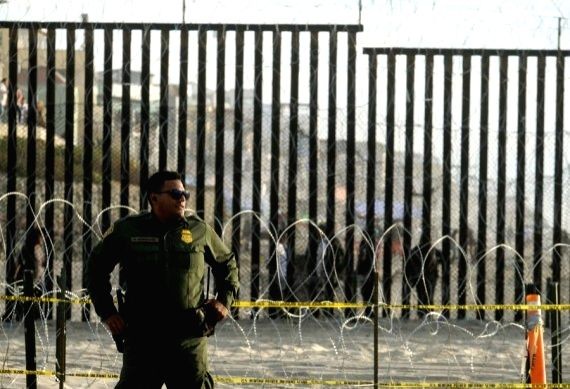 A U.S. Border Patrol agent stands in front of the border fence that divides the U.S. and Mexico in San Diego, California, the United States. (Xinhua/IANS File Photo)
