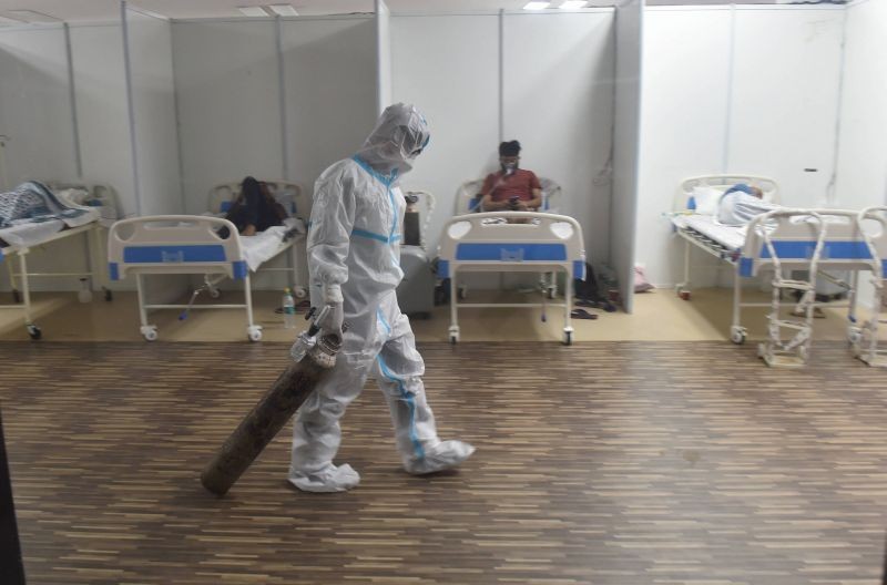 A doctor drags an oxygen cylinder at CWG village Covid-19 Care Centre near Akshardham, in New Delhi on April 20. (PTI Photo)