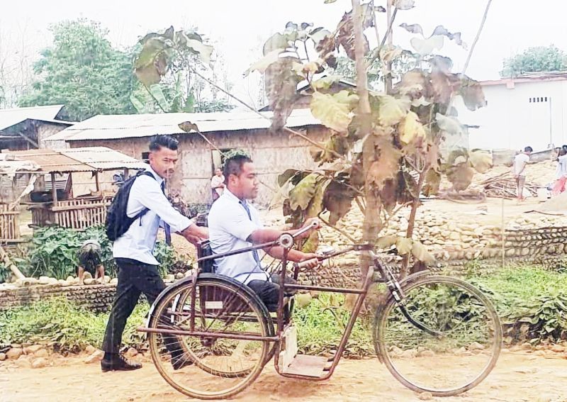 Ato(on tricycle) being helped by another student on their way to college on April 15. (Photo Courtesy: Hoto Yeptho)