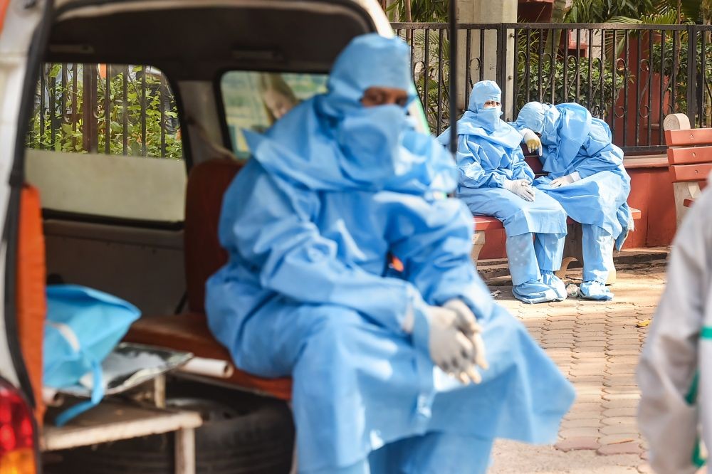 New Delhi: Family members, wearing PPE kits, wait during cremation of a COVID-19 victim, at the Nigambodh Ghat in New Delhi, Thursday, April 15, 2021. (PTI Photo/Arun Sharma)
