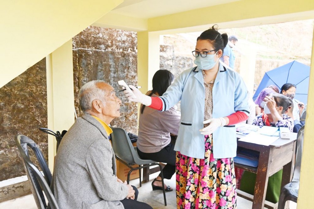 A health worker testing the temperature of a patient who came to avail the free medical services organized by Benpulin Semchir Telongjem at Government Middle School, Kumlong Ward on April 10. (Photo Courtesy: Imkongsenla)