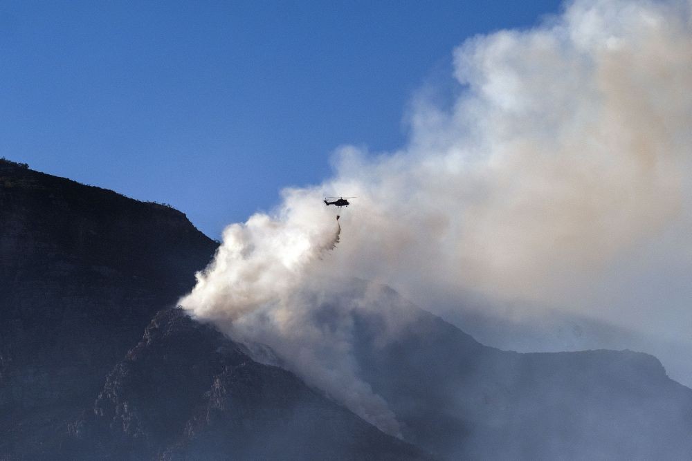 Cape Town : A South African military helicopter drops his water load on the top of Table Mountain in Cape Town, South Africa, Tuesday April 20, 2021. Fire crews worked for a third day to extinguish a wildfire on the slopes of Cape Town's Table Mountain on Tuesday as the city came to terms with the damage caused by what officials have described as one of the area's worst blazes in years. AP/PTI