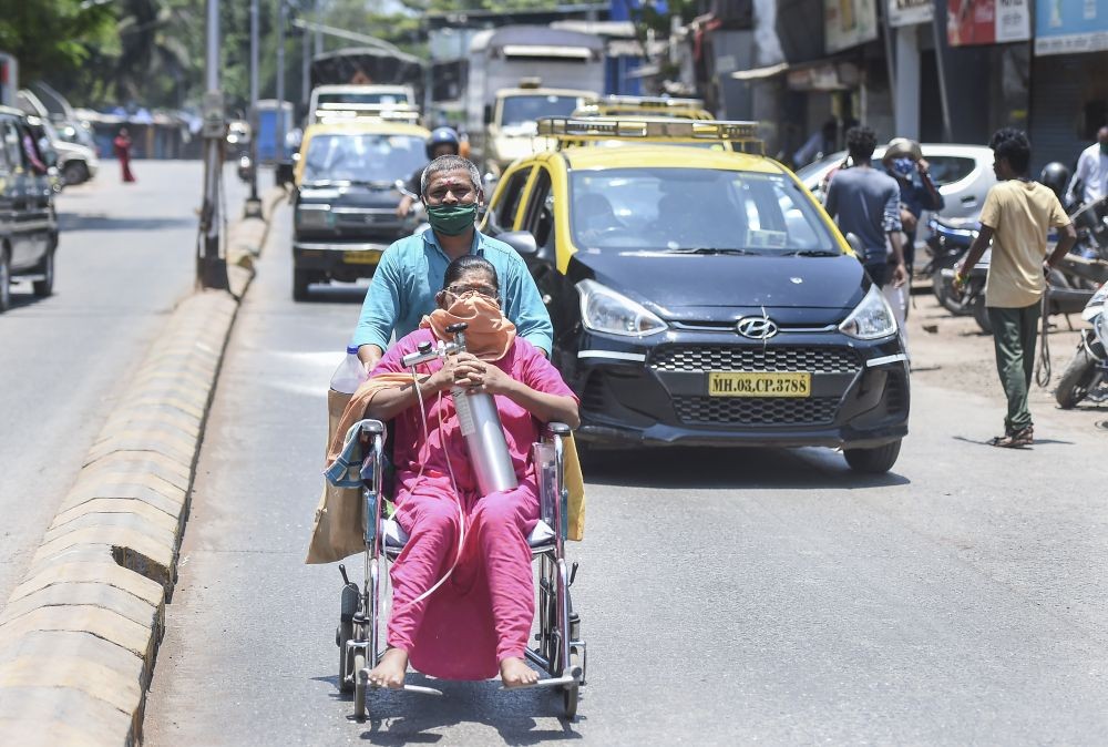 Mumbai: A patient, having breathing issues, carries an oxygen cylinder on her lap while being taken home after her discharge from a hospital, at Dharavi in Mumbai, Tuesday, May 11, 2021. (PTI Photo/Kunal Patil)