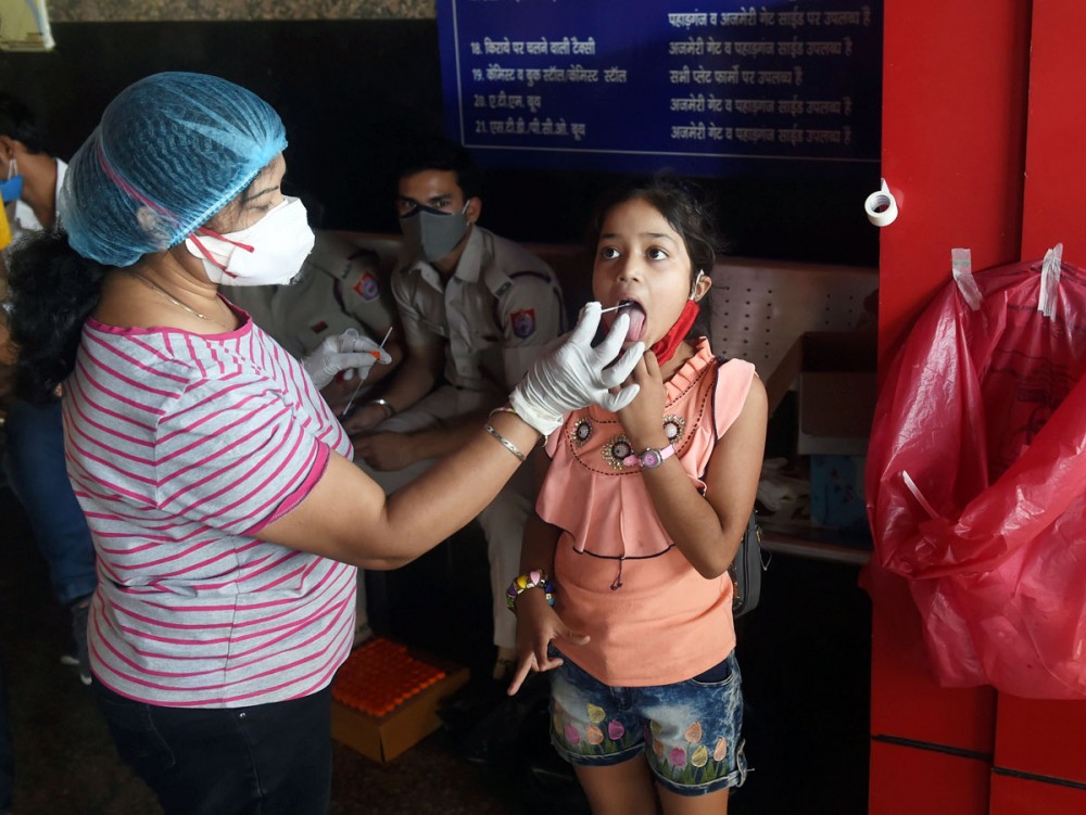 A health worker collects swab sample of a child passenger at a COVID-19 testing counter at New Delhi railway station. Photograph: Shahbaz Khan/PTI Photo