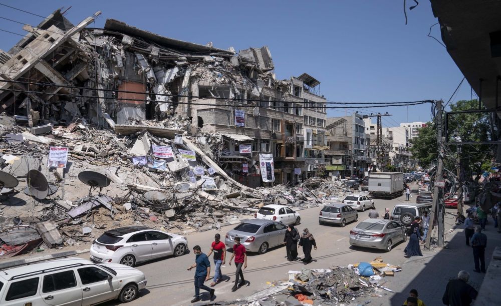 Gaza City: Motorists and pedestrians move past a building destroyed by an air-strike prior to a cease-fire that halted the 11-day war between Gaza's Hamas rulers and Israel, Tuesday, May 25, 2021, in Gaza City, the Gaza Strip. AP/PTI