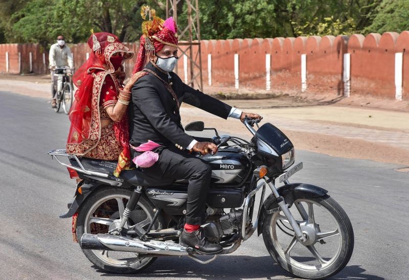 Bikaner: A couple rides on a bike after getting married amid second wave of COVID-19 pandemic in Bikaner, Thursday, May 27, 2021. (PTI Photo)