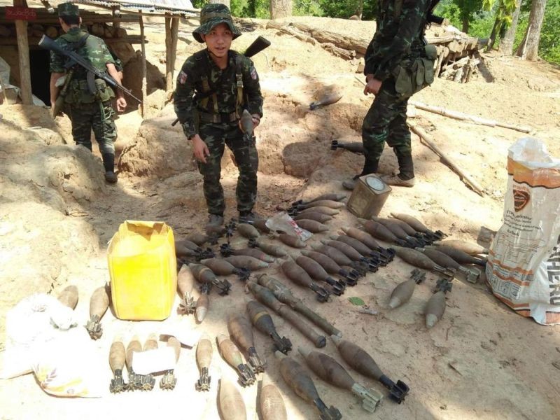 In this photo provided by Karen National Liberation Army, a Karen National Liberation Army soldier holds a motor shell while standing next to a cache of mortar shells found at a Myanmar military outpost Friday, May 7, 2021, in Mutraw district, Karen State, Myanmar. Ethnic Karen guerrillas burned down a Myanmar military outpost Friday morning, capturing it without a fight after its garrison fled at their approach, a senior Karen officer said. (AP Photo)