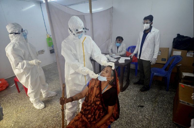 A health worker takes swab sample of a woman for COVID-19 test, at a railway station in Agartala on June 11, 2021. (PTI Photo)