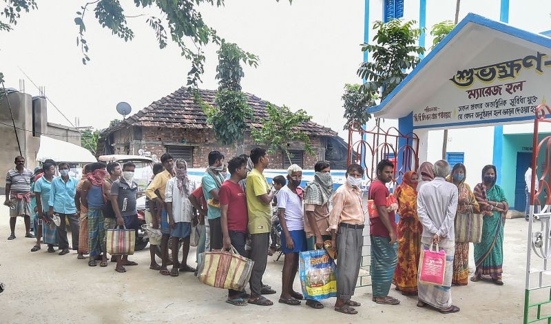 Villagers stand in a queue to collect relief material at Chitnan village of Vatora Island in Howrah on June 29, 2021. (PTI Photo)