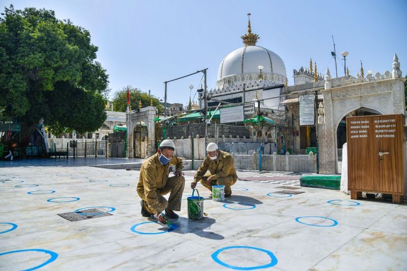Two workers paint circles following social distancing norms ahead of the reopening of Dargah Khwaja Gharib Nawaz as Rajasthan government allows religious places to reopen from Monday, in Ajmer on June 27, 2021. (PTI Photo)