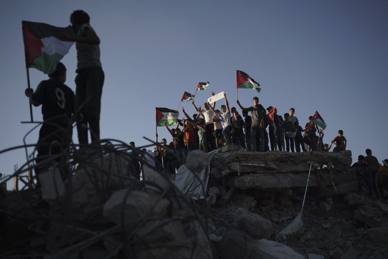 Protesters wave Palestinian flags as they stand atop the rubble of a building destroyed by an Israeli airstrike last month, during a protest against a march by Jewish ultranationalists through east Jerusalem, in Beit Lahia, northern Gaza Strip on June 15, 2021. (AP/PTI Photo)