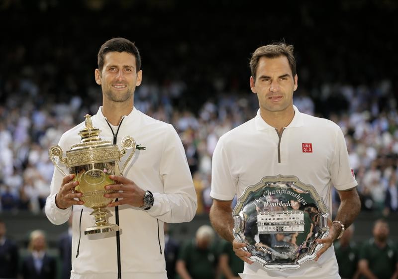 FILE - Serbia s Novak Djokovic, left, and Switzerland s Roger Federer pose with the trophies after the men s singles final match of the Wimbledon Tennis Championships in London, in this Sunday, July 14, 2019, file photo. There are plenty of intriguing story lines to follow on the grass courts. That includes Novak Djokovic s bid to equal Roger Federer and Rafael Nadal at 20 major titles and Serena Williams seeking her 24th. (AP Photo/Tim Ireland, File)