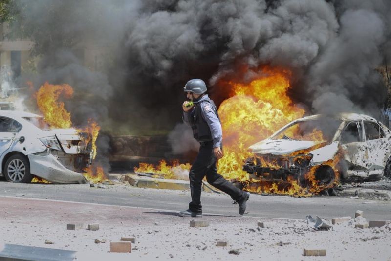 An Israeli firefighter walks next to cars hit by a missile fired from Gaza Strip, in the southern Israeli town of Ashkelon on May 11, 2021. (AP File Photo)