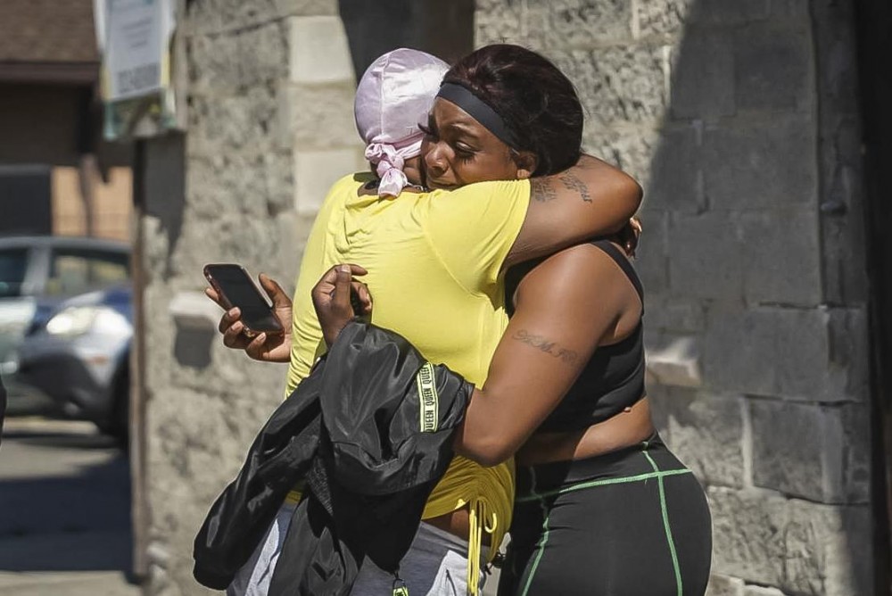 A woman receives a hug from a supporter outside the scene of a shooting outside a home in Chicago, Tuesday, June 15, 2021. Police say an argument at a house on Chicago's South Side erupted in fatal gunfire, leaving some dead and others injured. (Ashlee Rezin Garcia /Chicago Sun-Times via AP)