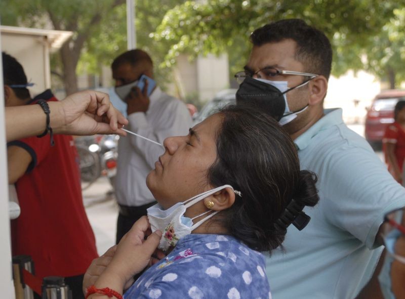A medical worker collects swab sample of a woman for COVID-19 test, at a district hospital in Noida on June 25. (PTI Photo)