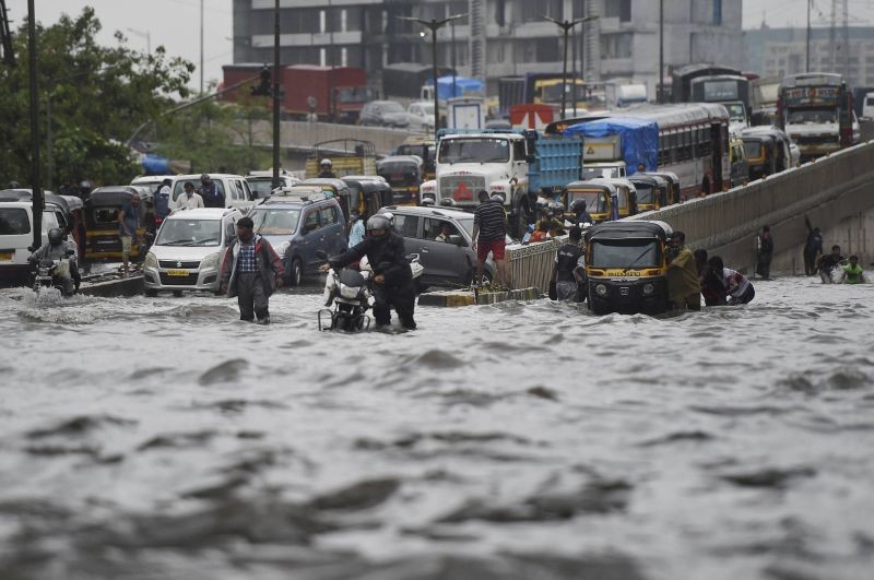 Commuters wade through a waterlogged street as heavy rain continues, at Santacruz-Chembur Link Road in Mumbai on June 12, 2021. (PTI Photo)