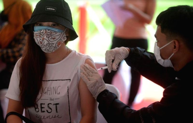 A health worker administers a dose of COVID-19 vaccine to a woman during a mass vaccination campaign in Jakarta, Indonesia on June 26, 2021. (IANS File Photo )