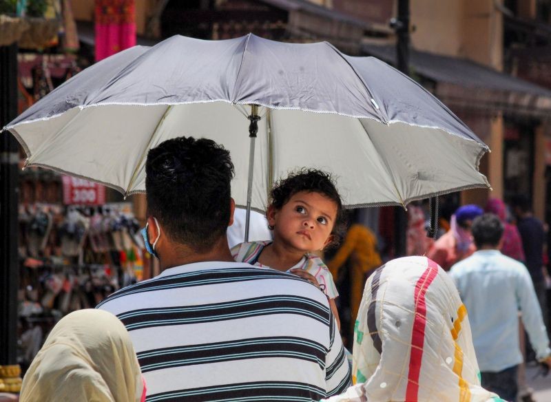 Amritsar: A man protects his child with an umbrella on a hot summer day, in Amritsar, Wednesday, June 9, 2021. (PTI Photo)(