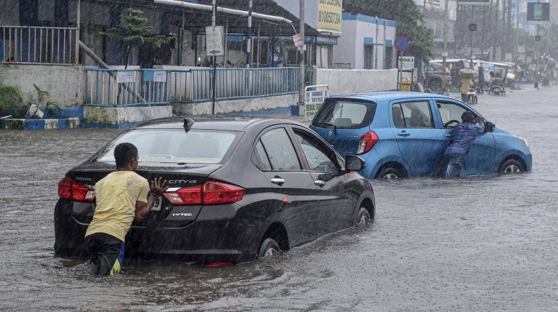 Kolkata: Commuters push their vehicles through a waterlogged area during heavy rain in Kolkata, Thursday, July 29, 2021. (PTI Photo)