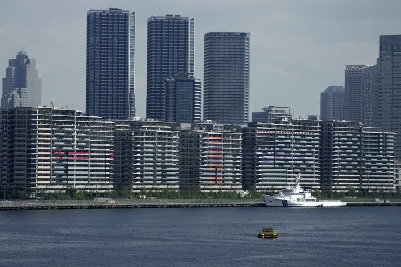 National banners hang from balconies at an athlete's village as Tokyo prepares for the 2020 Summer Olympics, Saturday, July 17, 2021. The pandemic-delayed games open on July 23 without spectators at most venues. (AP Photo/Charlie Riedel)
