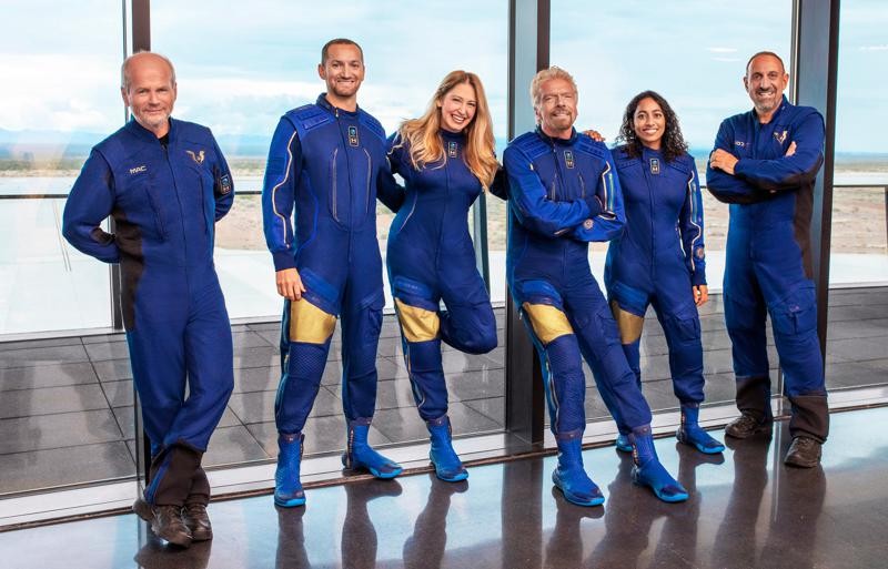 This image provided by Virgin Galactic shows, from left: Chief Pilot Dave Mackay, Lead Operations Engineer Colin Bennett, Chief Astronaut Instructor Beth Moses, Founder of Virgin Galactic Richard Branson, Vice President of Government Affairs and Research Operations Sirisha Bandla and pilot Michael Masucci. Branson is aiming to beat fellow billionaire Jeff Bezos into space by nine days. Branson’s company announced Thursday, July 1, 2021 that its next test flight will be July 11 and that its founder will be among the six people on board. The winged rocket ship will soar from New Mexico _ the first carrying a full crew of company employees. It will be only the fourth trip to space for Virgin Galactic. (Virgin Galactic via AP)