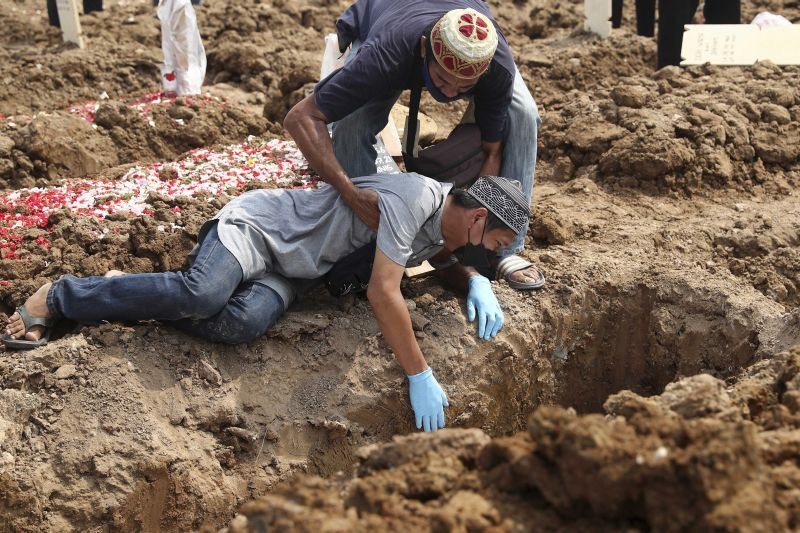 A man falls on the ground as he weeps during the burial of a relative who died of COVID-19 at Rorotan Cemetery in Jakarta, Indonesia on July 7, 2021. (AP/PTI Photo)