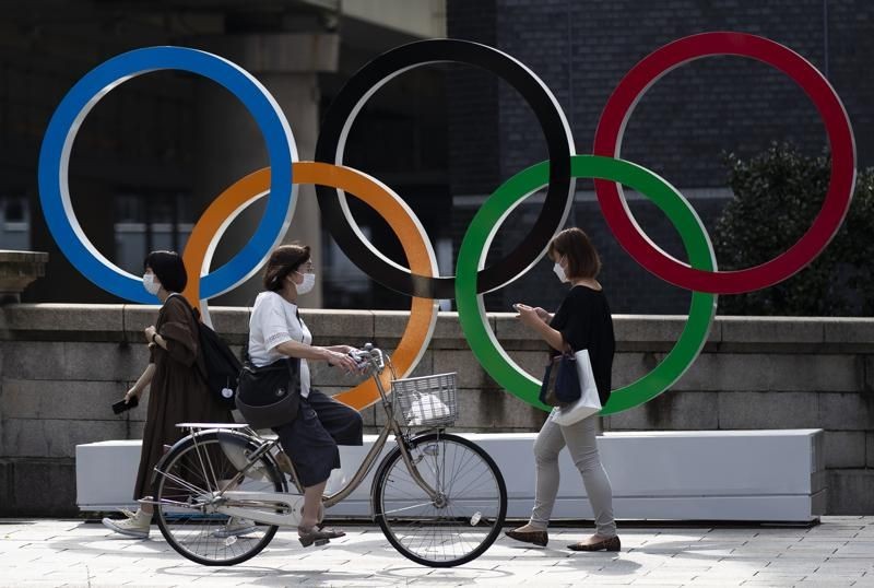 In this July 15, 2021, file photo, people walk by the Olympic rings installed by the Nippon Bashi bridge in Tokyo. A Ugandan athlete who fled during his pre-game training in western Japan last week has been found and being interviewed by police, officials said Tuesday on July 20. (AP Photo)