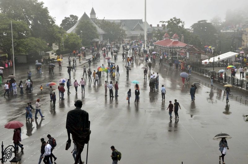 People use umbrellas to protect themselves during rain at Ridge in Shimla on Tuesday, July 13, 2021. (PTI Photo)