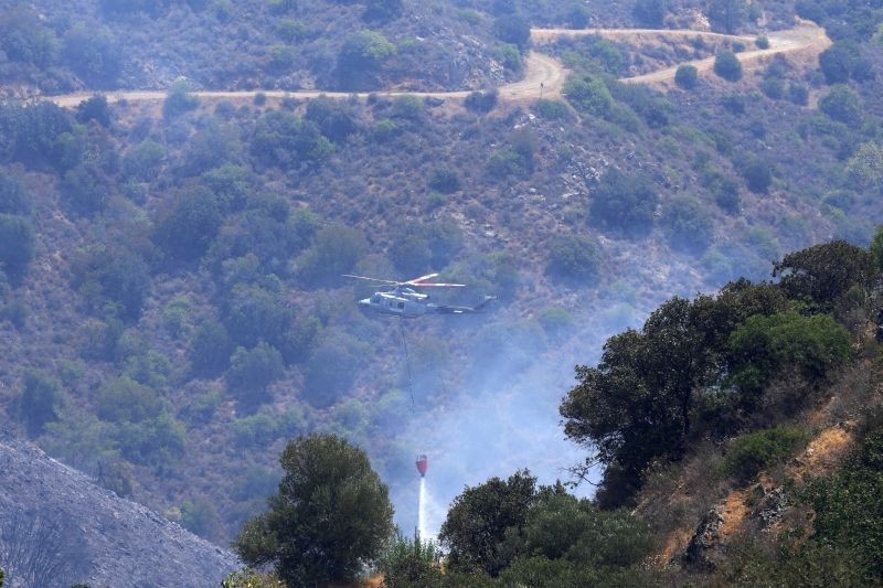 An helicopter drops water over the mountain of Troodos in Agious Vavatsinias village, southwestern Cyprus on July 4, 2021. Cyprus search crews discovered the bodies of four people outside a fire-swept mountain village on Sunday in what a government minister called the "most destructive" blaze in the east Mediterranean island nation's history. (AP/PTI Photo)