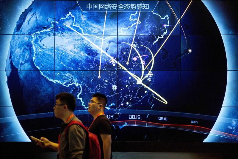 In this Sept. 12, 2017, file photo, attendees walk past an electronic display showing recent cyberattacks in China at the China Internet Security Conference in Beijing. Tech experts in China who find a weakness in computer security would be required to tell the government instead of publicizing it under rules announced Tuesday, July 13, 2021, as part of the ruling Communist Party’s sweeping effort to tighten control over information. (AP Photo/Mark Schiefelbein, File)