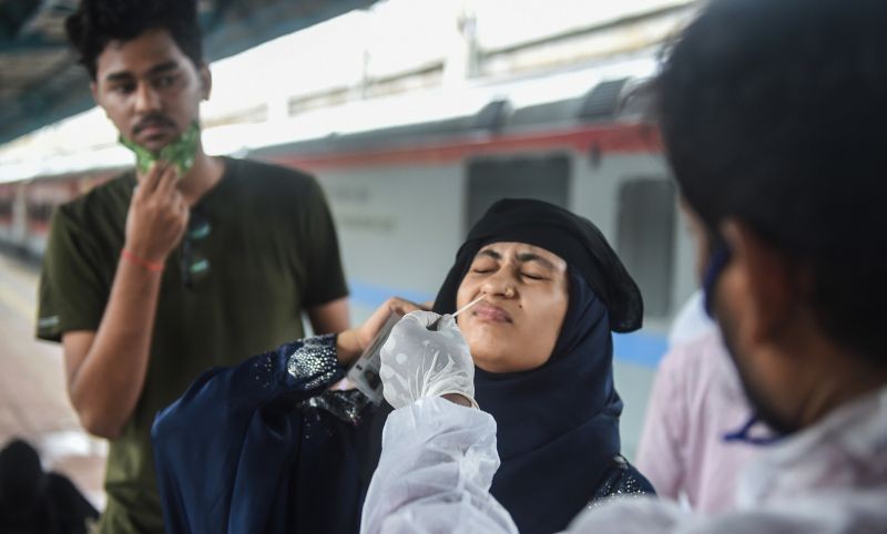 A BMC health worker collects swab sample of a passenger for COVID-19 test, at a station in Mumbai on July 11, 2021. (PTI Photo)