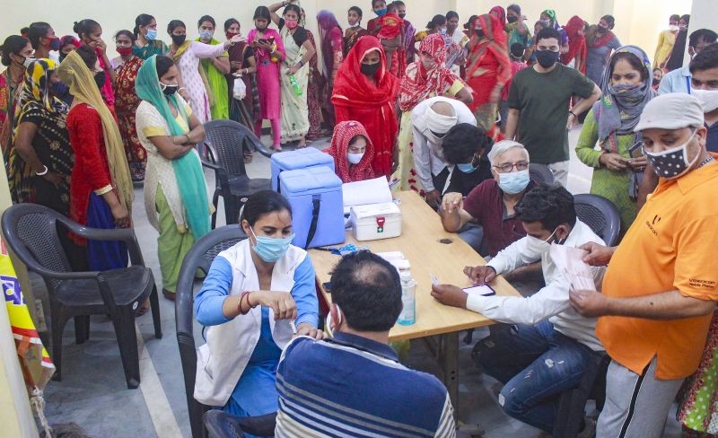 A health worker administers a dose of Covid-19 vaccine to a beneficiary as others wait in queues, at a vaccination camp at a slum area in Gurugram on July 4. (PTI Photo)