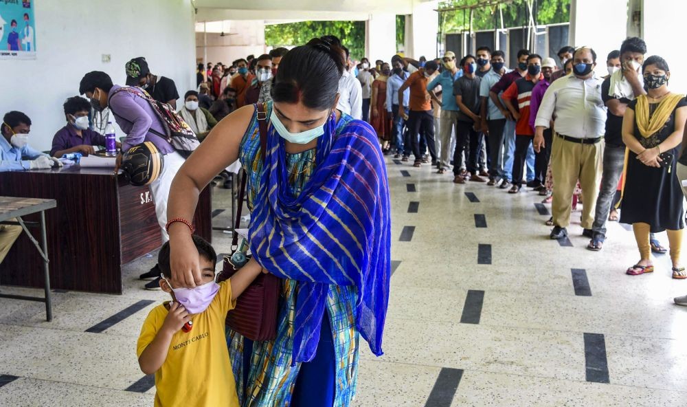 Patna: A beneficiary adjusts the face mask of her child before receiving a dose of COVID-19 vaccine, at SKM hall in Patna, Thursday, July 15, 2021. (PTI Photo)