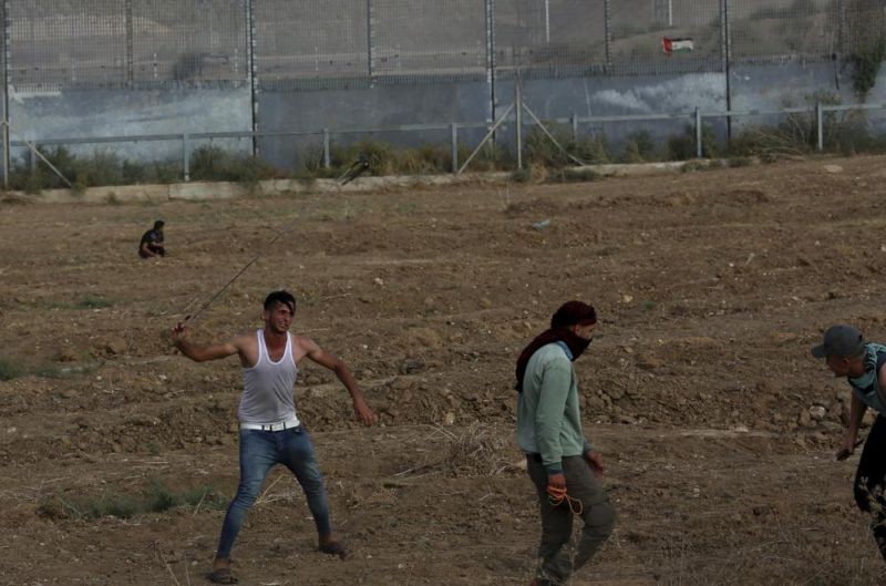 Protestors hurl stones at Israeli troops near the fence of Gaza Strip border with Israel, during a protest marking the anniversary of a 1969 arson attack at Jerusalem's Al-Aqsa mosque by an Australian tourist later found to be mentally ill, east of Gaza City on August 21, 2021. (AP Photo)