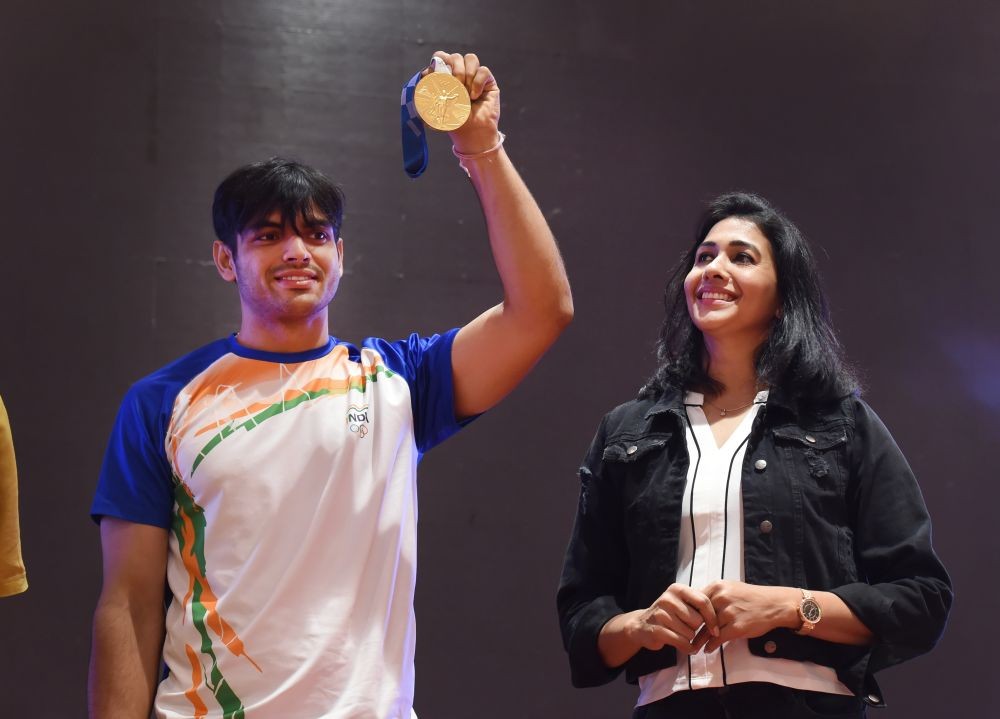 New Delhi: Neeraj Chopra, who won gold medal in the javelin throw event of the recently concluded Tokyo Olympics 2020, shows his medal as former athlete Anju Bobby George looks on, at a press conference in New Delhi, Tuesday, Aug 10, 2021. (PTI Photo/Atul Yadav)