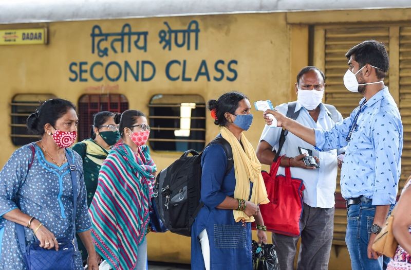 A health worker checks body temperature of a traveler as a precaution against the coronavirus before allowing them to proceed, at a railway station in Mumbai on August 20, 2021. (PTI Photo)