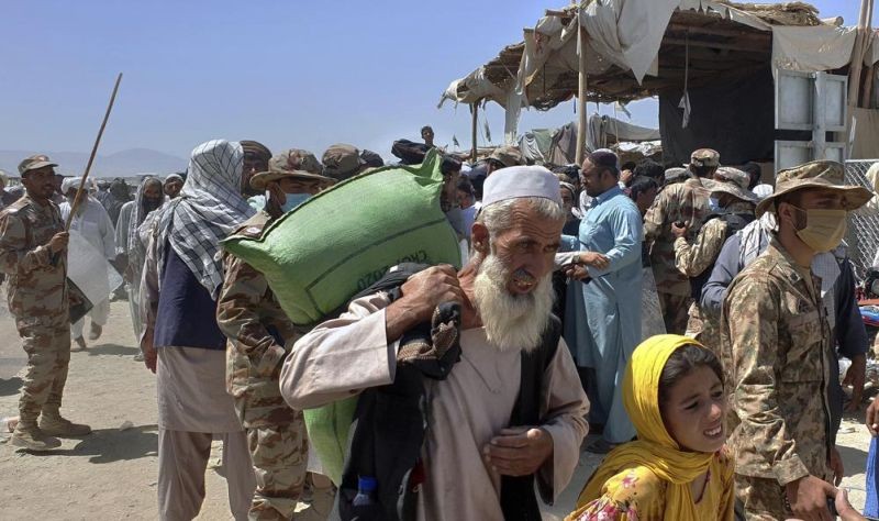 Pakistani soldiers stand guard while stranded people walk towards the Afghan side at a border crossing point, in Chaman, Pakistan on  August 13, 2021. Pakistan opened its Chaman border crossing for people who had been stranded in recent weeks. Juma Khan, the Pakistan border town's deputy commissioner, said the crossing was reopened following talks with the Taliban. (AP Photo)