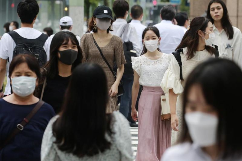 People wearing face masks to help protect against the spread of the coronavirus walk across an intersection on August 24, 2021. (AP Photo)