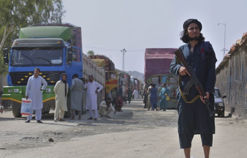 A Taliban fighter stands guard on Afghan side while people wait to cross at a border crossing point between Pakistan and Afghanistan, in Torkham, in Khyber district, Pakistan on August 21, 2021. In the current situation of Afghanistan, pedestrian movement has limited in Torkham border, only stranded people in both sides and trucks taking goods to Afghanistan can passes through this border point. (AP/PTI Photo)
