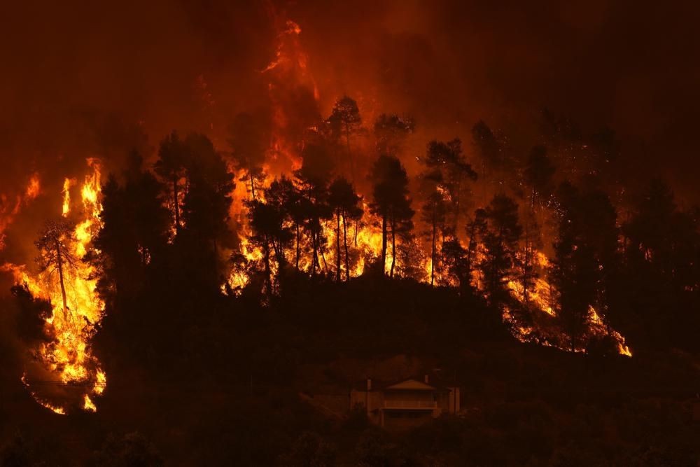 Flames approaching at Gouves village on the island of Evia, about 185 kilometers (115 miles) north of Athens, Greece, Sunday, Aug. 8, 2021. Pillars of billowing smoke and ash are blocking out the sun above Greece's second-largest island as a days-old wildfire devours pristine forests and triggers more evacuation alerts. (AP Photo/Petros Karadjias)